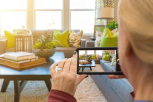 Blonde woman taking a picture of her living room on a phone