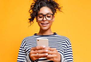 Girl smiling at her phone with a yellow background